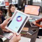 Business team using a tablet to analyze digital marketing data with charts in an office setting.