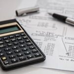 Close-up of financial documents with calculator and pen, ideal for business management themes.