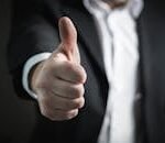 A close-up of a man's thumbs up gesture, symbolizing success and agreement.
