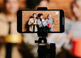 Diverse group of friends filming a video with a smartphone on a tripod indoors.